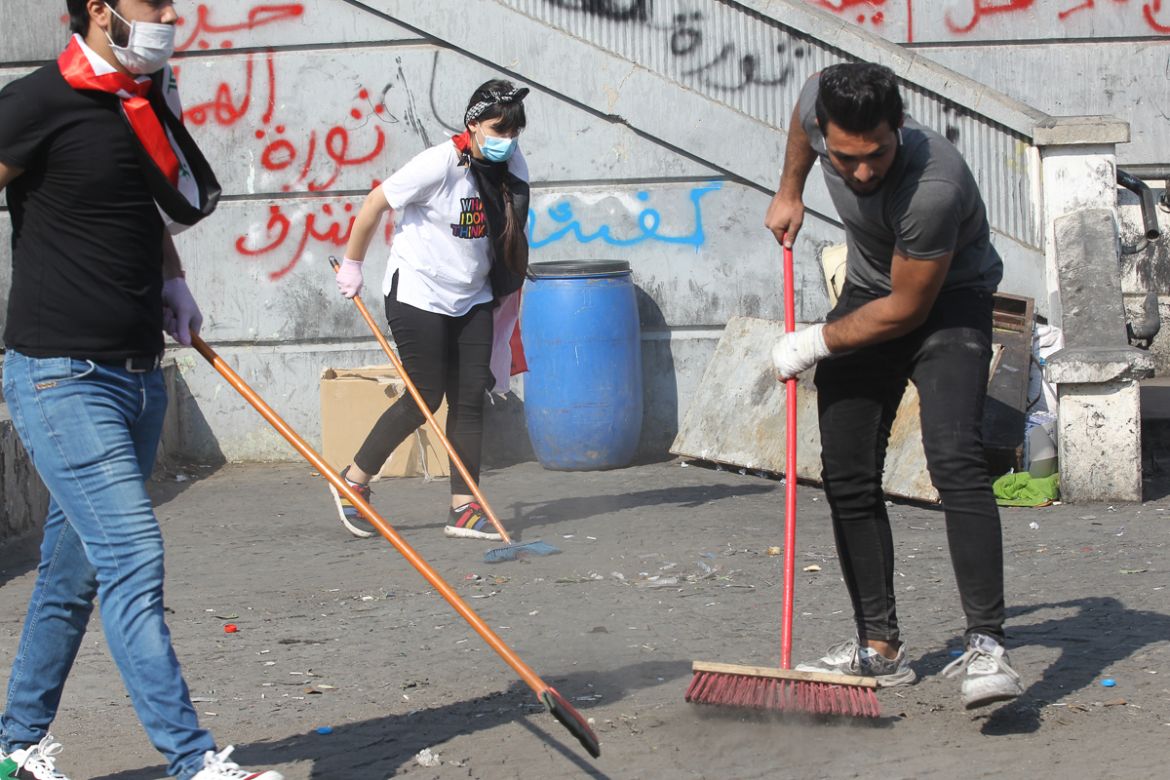 Iraqis sweep away waste left behind by fellow demonstrators near al-Jumhuriya bridge which leads to the high-security Green Zone, during ongoing anti-government protests in the capital Baghdad on Nove