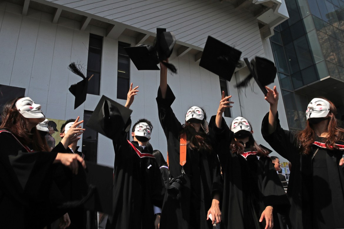 University students wearing Guy Fawkes masks throw their hats after their graduation ceremony at the Chinese University of Hong Kong, in Hong Kong, Thursday, Nov. 7, 2019. (AP Photo/Kin Cheung)