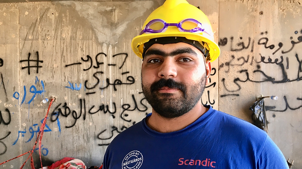  Abdullah stands inside one of the building’s makeshift bedrooms  [Sofia Barbarani/Al Jazeera]