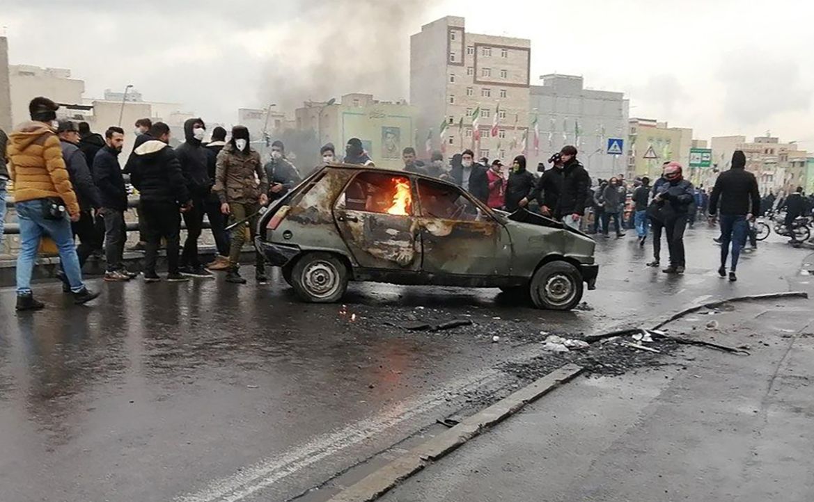 Iranian protesters gather around a burning car during a demonstration against an increase in gasoline prices in the capital Tehran, on November 16, 2019. - One person was killed and others injured in