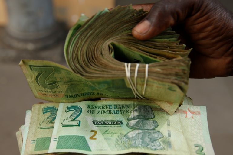 A street vendor poses as he displays bond notes, before the introduction of new currency in Harare