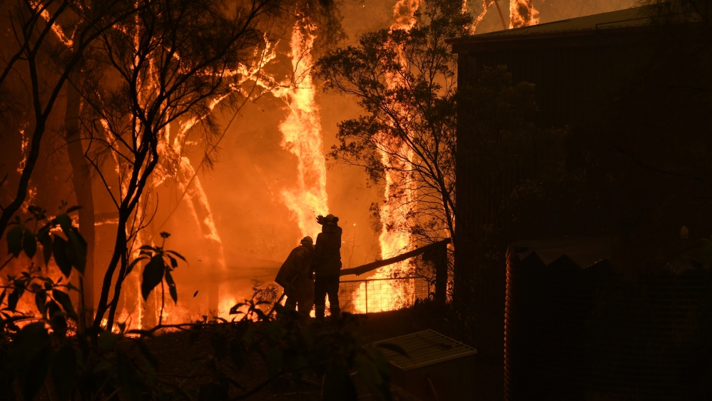 RFS volunteers and NSW Fire and Rescue officers protect a home on Wheelbarrow Ridge Road being impacted by the Gospers Mountain fire near Colo Heights south west of Sydney