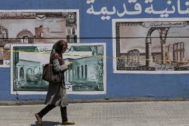 A woman walks by a wall painted with images of Lebanon''s old currency along a street of the Arab University in Beirut August 10, 2012