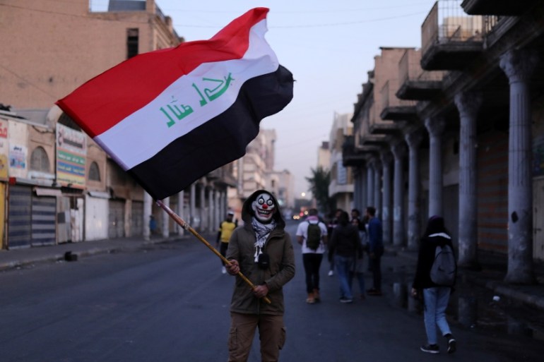An Iraqi demonstrator holds an Iraqi flag during ongoing anti-government protests, in Baghdad