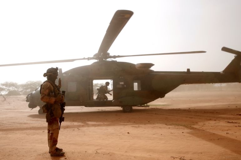 A French soldier stands guards in front of an NH90 Caiman military helicopter during Operation Barkhane in Ndaki