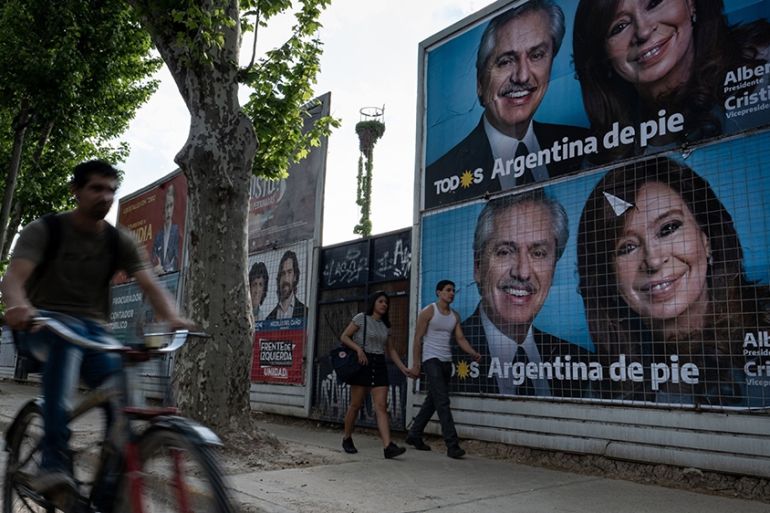 Pedestrians walk by campaign posters for Alberto Fernandez, presidential candidate for Frente de Todos party, ahead of presidential elections in Buenos Aires on Saturday, Oct. 26, 2019. Ar
