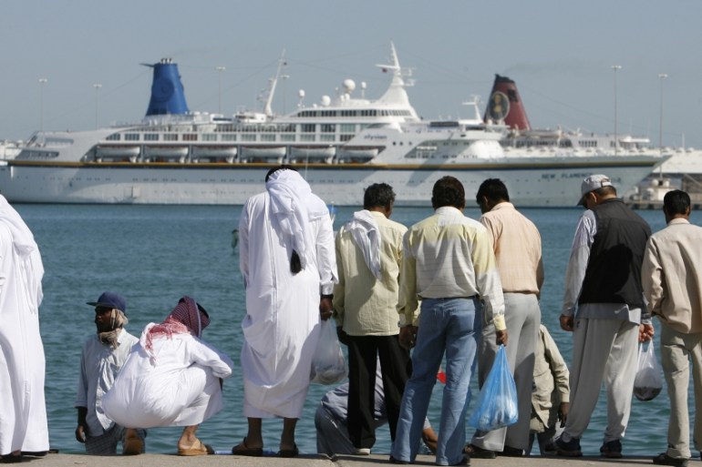 A cruise ship moors off the coast of central Doha behind men buying fish from local fishermen on the corniche 28 November 2006, three days before the 15th Asian Games open in the Qatari capital. With