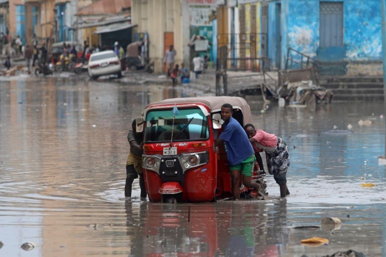 Somali men push their rickshaw through flood waters after a rainfall in Mogadishu, Somalia