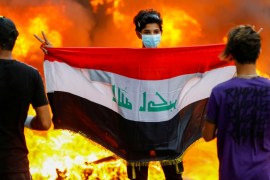 A demonstrator carries an Iraqi flag during ongoing anti-government protests in Baghdad