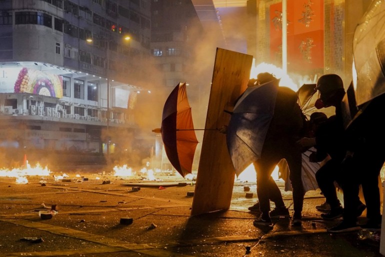 Protestors react as police fire tear gas in the Kowloon area of Hong Kong, Monday, Nov. 18, 2019. As night fell in Hong Kong, police tightened a siege Monday at a university campus as hundreds of anti