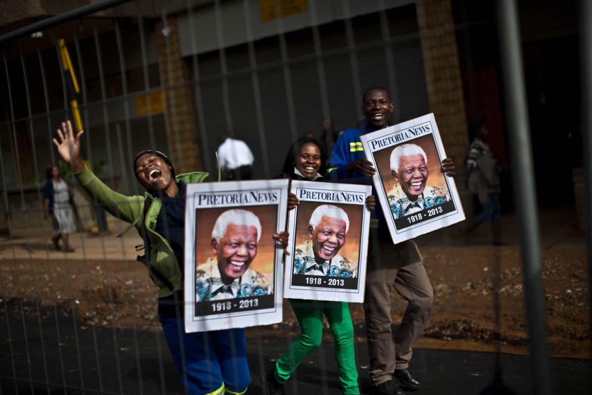 South African mourners hold posters of former president Nelson Mandela, while chanting slogans as the convoy transporting the body of Nelson Mandela passes by, in Pretoria, South Africa, Wednesday, De