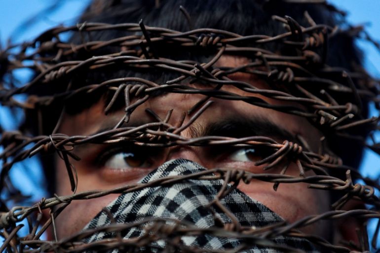 A masked Kashmiri man with his head covered with barbed wire attends a protest after Friday prayers during restrictions following the scrapping of the special constitutional status for Kashmir by the