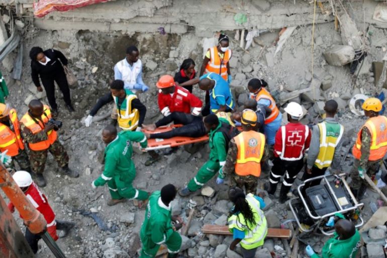 An injured women rescued from the rubble is carried by rescuers at the scene where a building collapsed in Nairobi