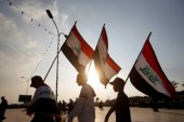Demonstrators carry Iraqi flags during continuing anti-government protests in Basra, Iraq [Essam al-Sudani/Reuters]