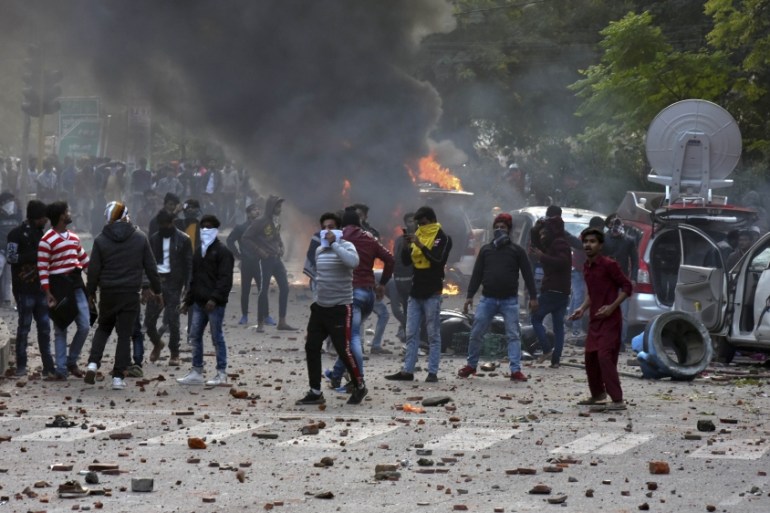 People throw stones at police as broadcast vans of television channels go up in flames during protests against India''s new citizenship law in Lucknow, India, Thursday, Dec. 19, 2019