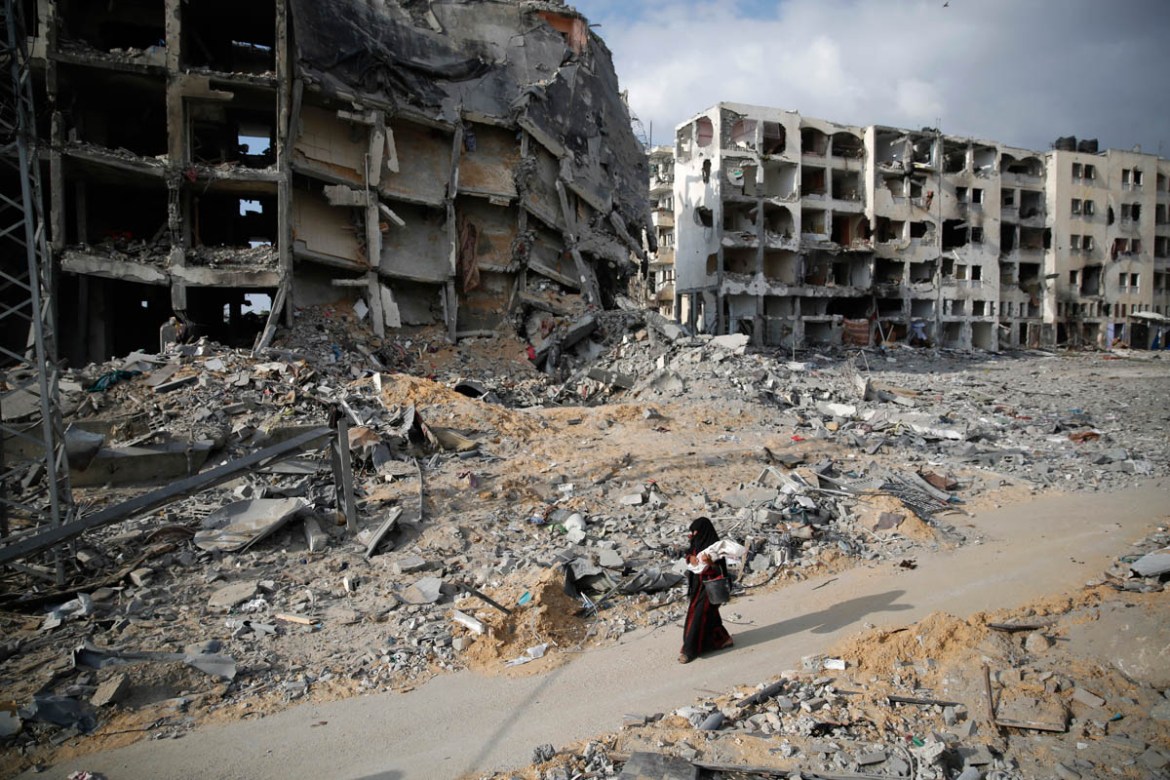 A Palestinian woman walks past buildings destroyed by what police said were Israeli air strikes and shelling in the town of Beit Lahiya in the northern Gaza Strip August 3, 2014. An Israeli air strike