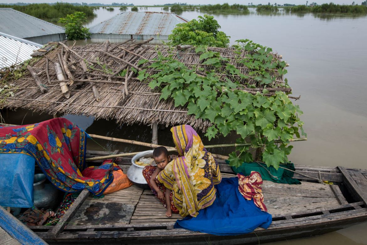 A mother and child living on a boat near their submerged house near Brahmaputra river on the northern side of Bangladesh