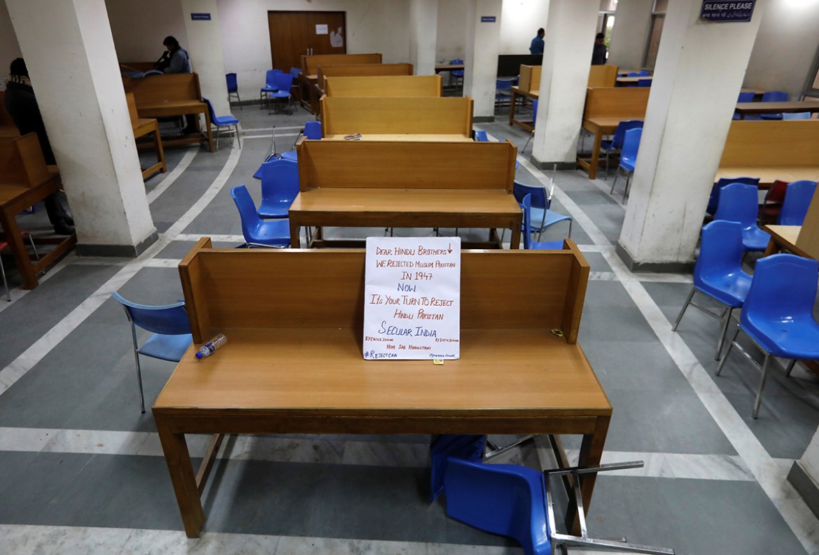 A placard lies on a table inside a partially damaged library of the Jamia Millia Islamia university after police entered the university campus on the previous day, following a protest against a new ci