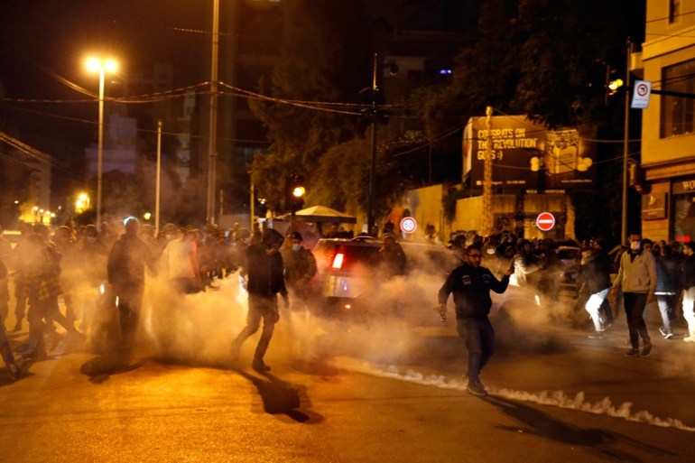 Protesters are seen surrounded by tear gas that was fired towards them by Lebanese riot police during an anti-government protest in Beirut, Lebanon, Wednesday, Dec. 4, 2019.