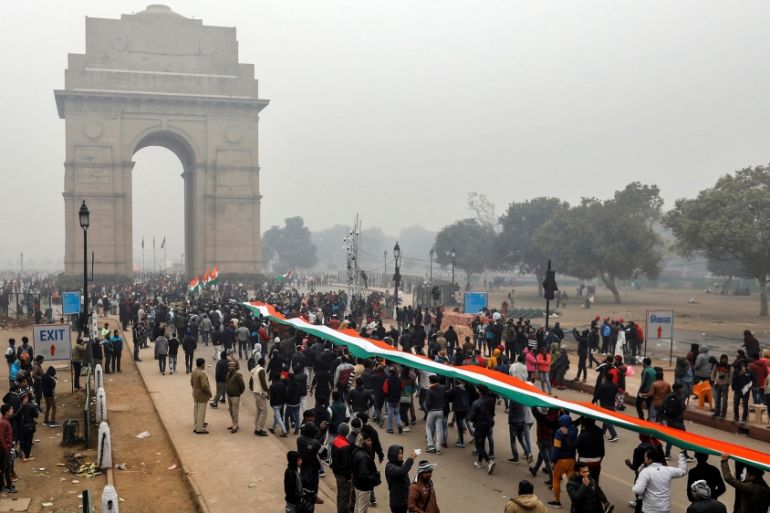 Demonstrators hold a tricoloured flag in front of the India Gate during a demonstration against what they say was an alleged police action conducted during recent protests against a new citizenship la