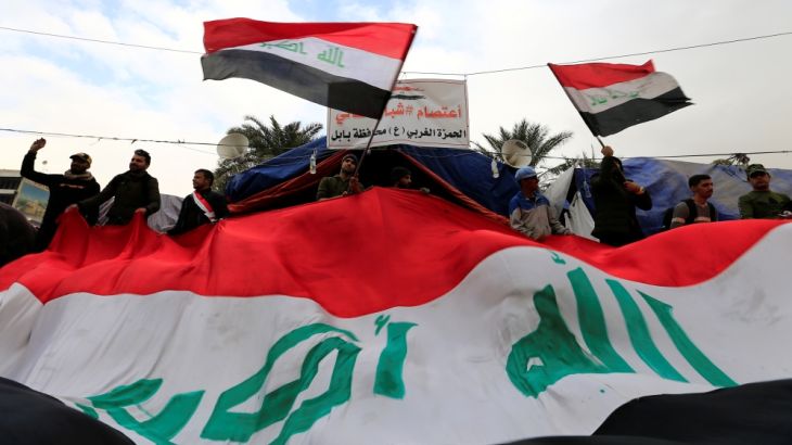 Iraqi demonstrators carry Iraqi flags during ongoing anti-government protests, in Baghdad
