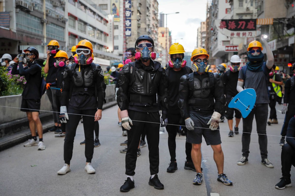 Protesters with protection gears face with riot policemen on a street during the anti-extradition bill protest in Hong Kong, Sunday, Aug. 11, 2019. Police fired tear gas late Sunday afternoon to try t