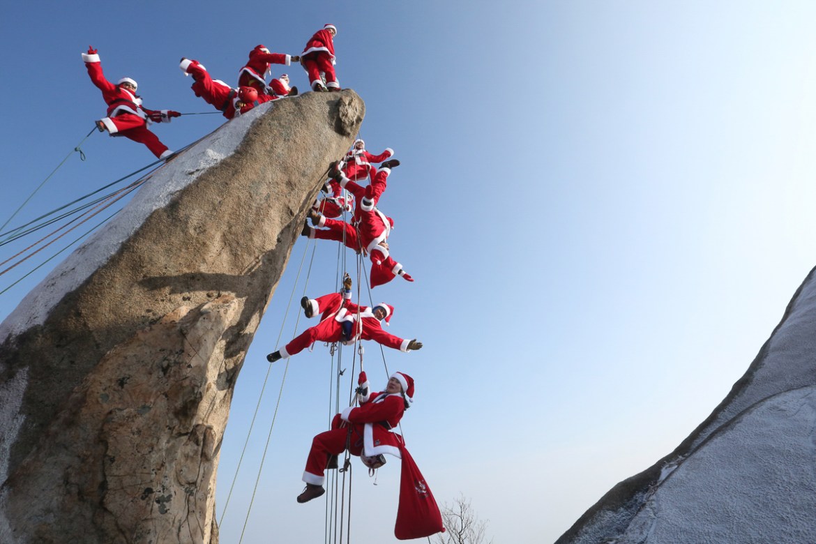 Mountain climbers in Santa Claus outfits pose during an event to hope for safe climbing and to promote Christmas charity on the Buckhan mountain in Seoul, South Korea. [Ahn Young-joon/AP Photo]