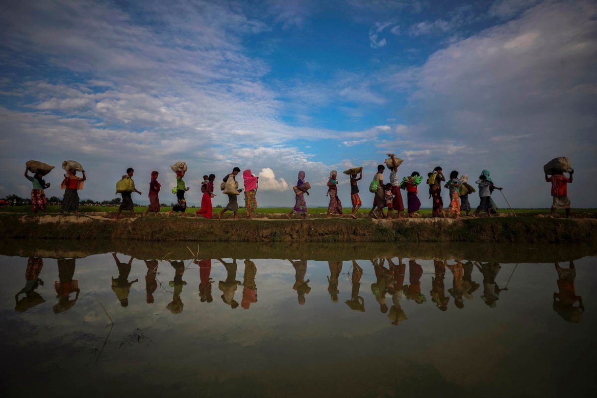Rohingya refugees are reflected in rain water along an embankment next to paddy fields after fleeing from Myanmar into Palang Khali, near Cox''s Bazar, Bangladesh November 2, 2017. REUTERS/Hannah McKay
