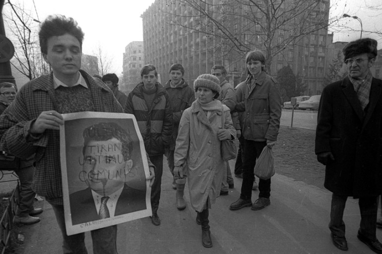 A man holds a picture of Nicolae Ceausescu during an uprising in Bucharest