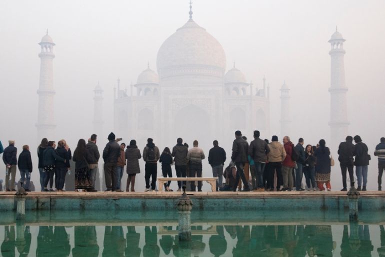 Visitors look toward the Taj Mahal through morning air pollution in Agra, India, January 12, 2019. Picture taken January 12, 2019. REUTERS/Andrew Kelly.