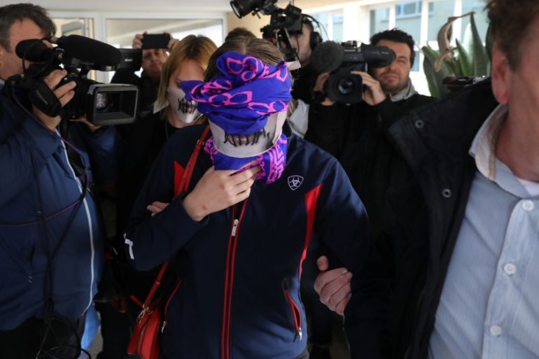 A British woman, accused of lying about being gang raped, covers her face as she leaves Famagusta courthouse in Paralimni