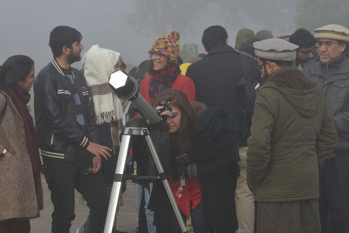 A woman watches a solar eclipse with a telescope in Islamabad on December 26, 2019. (Photo by Farooq NAEEM / AFP)