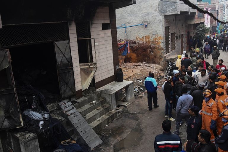 People gather around a warehouse where a fire broke out in the early hours of Monday at Kirari area of New Delhi, India, Monday, Dec.23, 2019. The blaze killed 9 people and left at least 3 injured, a