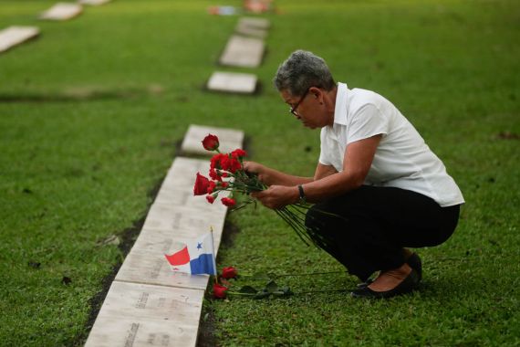A woman places flowers on the grave of a person who died during the 1989 U.S. military invasion that ousted Panamanian strongman Manuel Noriega, on the 30th anniversary of the invasion in Panama City,