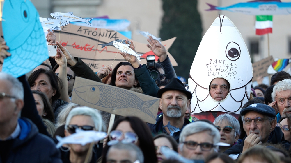 A demonstrator shows a sardine-shaped banner reading 