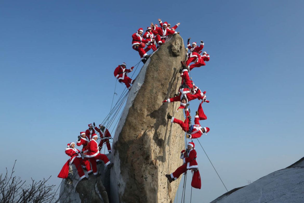 Mountain climbers in Santa Claus outfits pose during an event to hope for safe climbing and to promote Christmas charity on the Buckhan mountain in Seoul, South Korea, Sunday, Dec. 22, 2019. (AP Phot