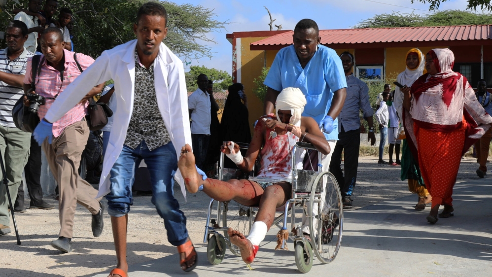 Paramedics and civilians assist a man injured in a car bomb explosion at a security checkpoint as he arrives to a hospital in Mogadishu