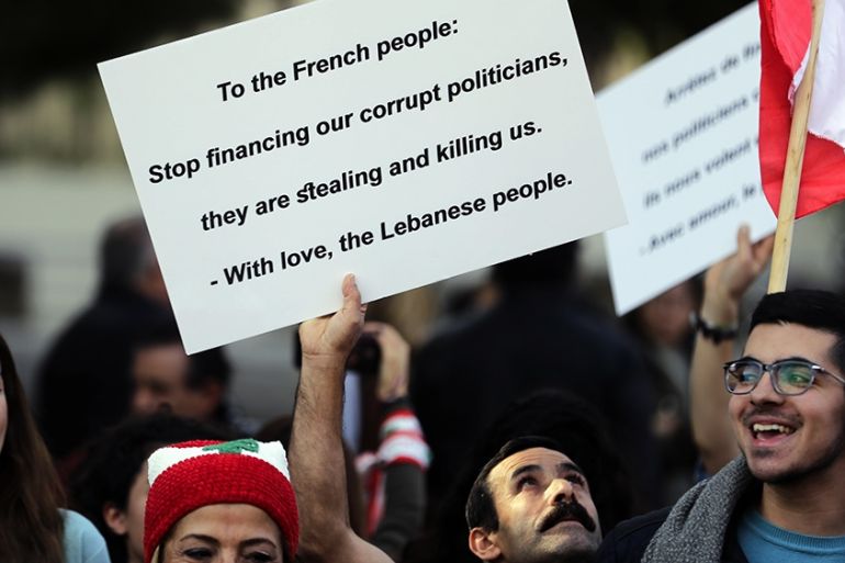 Lebanese anti-government demonstrators hold placards outside the French embassy in the capital Beirut on December 11, 2019