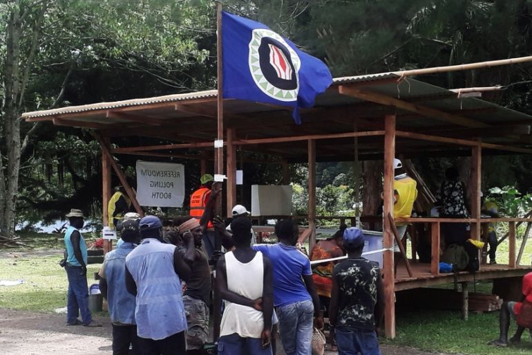 Residents hold a Bougainville flag at a polling station during a non-binding independence referendum in Arawa