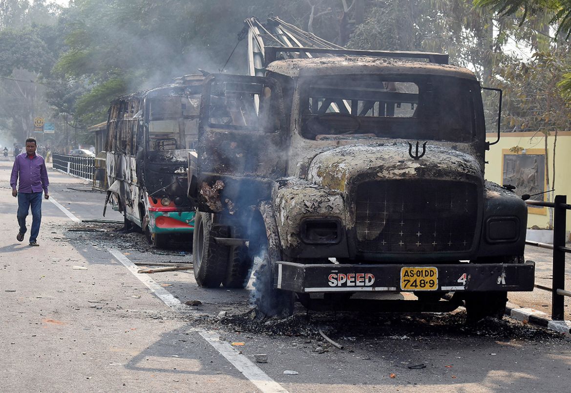 A man walks past damaged vehicles that were set on fire by demonstrators, during a protest after India''s parliament passed Citizenship Amendment Bill, in Guwahati, India December 12, 2019. REUTERS/Anu