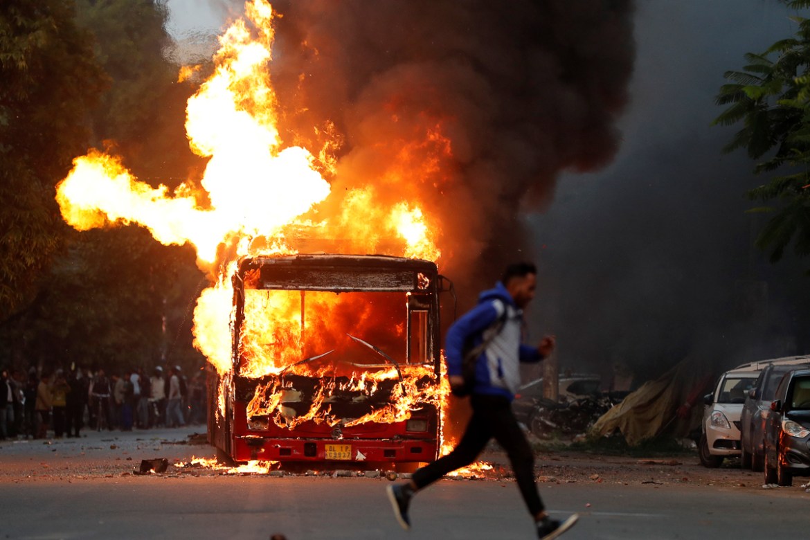 A man runs past a burning bus that was set on fire by demonstrators during a protest against a new citizenship law, in New Delhi, India, December 15, 2019. REUTERS/Adnan Abidi