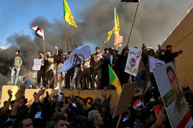 Protesters burn property in front of the U.S. embassy compound, in Baghdad, Iraq, Tuesday, Dec. 31, 2019. Dozens of angry Iraqi Shiite militia supporters broke into the U.S. Embassy compound in Baghda