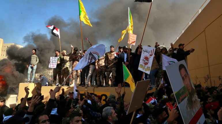 Protesters burn property in front of the U.S. embassy compound, in Baghdad, Iraq, Tuesday, Dec. 31, 2019. Dozens of angry Iraqi Shiite militia supporters broke into the U.S. Embassy compound in Baghda