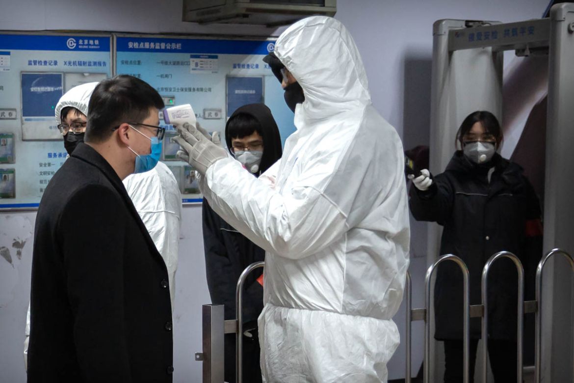 A worker wearing a hazardous materials suit takes the temperature of a passenger at the entrance to a subway station in Beijing, Sunday, Jan. 26, 2020. The new virus accelerated its spread in China, a