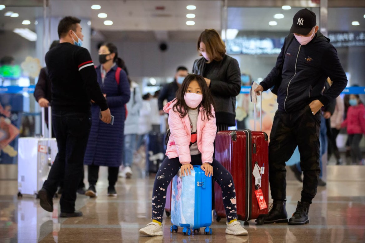 Travelers wear face masks as they stand in the arrivals area at Beijing Capital International Airport in Beijing, Thursday, Jan. 23, 2020. China closed off a city of more than 11 million people Thursd