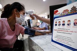 A nurse checks a patient?s body temperature next to a campaign poster alerting on the coronavirus at a hospital in Bangkok, Thailand, 22 January 2020. The SARS-like coronavirus was detected in three C