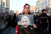 An Iranian man holds a picture of General Qassem Soleimani during his funeral procession in Tehran on January 6, 2020 [Nazanin Tabatabaee/WANA via Reuters]
