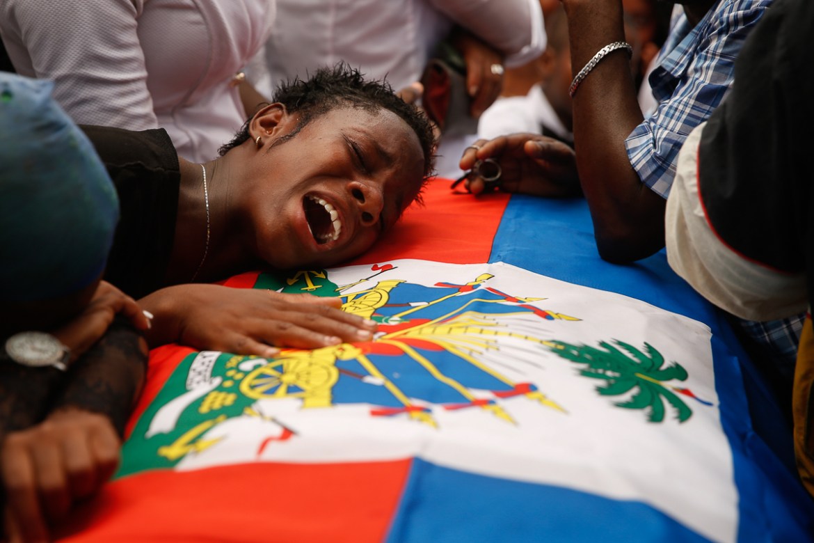 A woman cries on a flag-draped coffin that contain the remains of a 16-year-old boy killed during a month of demonstrations aimed at ousting President Jovenel Moi¨se, at a joint funeral in a public pl