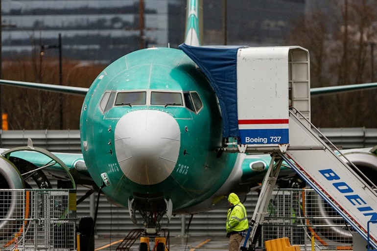 An employee walks past a Boeing 737 Max aircraft seen parked at the Renton Municipal Airport in Renton, Washington, U.S. January 10, 2020