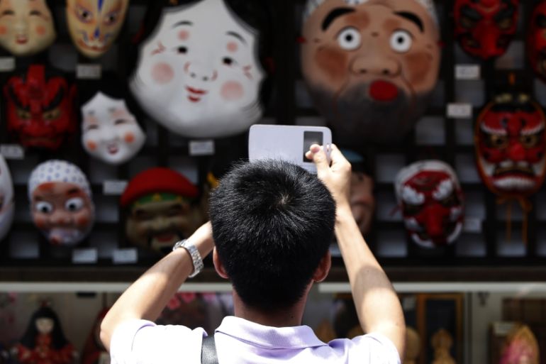 A tourist from China takes pictures of Japanese traditional masks